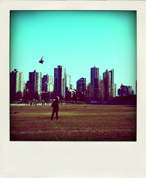 Lady flying a kite behind the backdrop of Vancouver polaroid